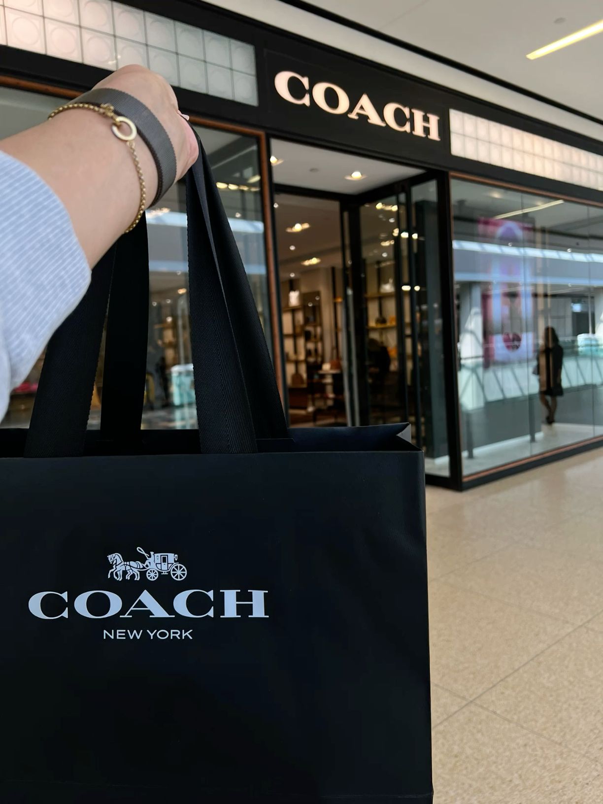 Coach shopping bag outside a Coach store
